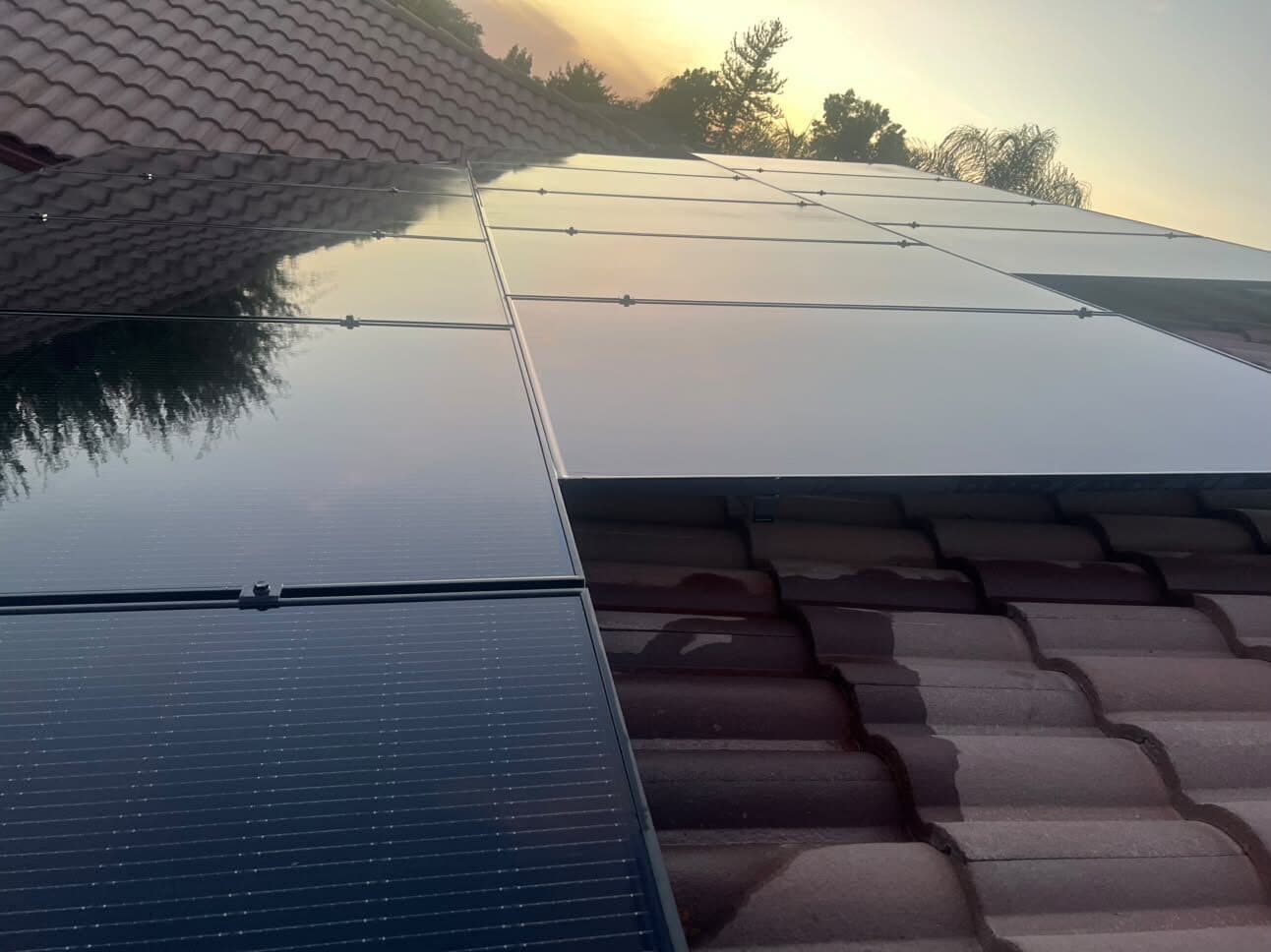 Close view of clean panel glass reflecting the sunset on a tile roof