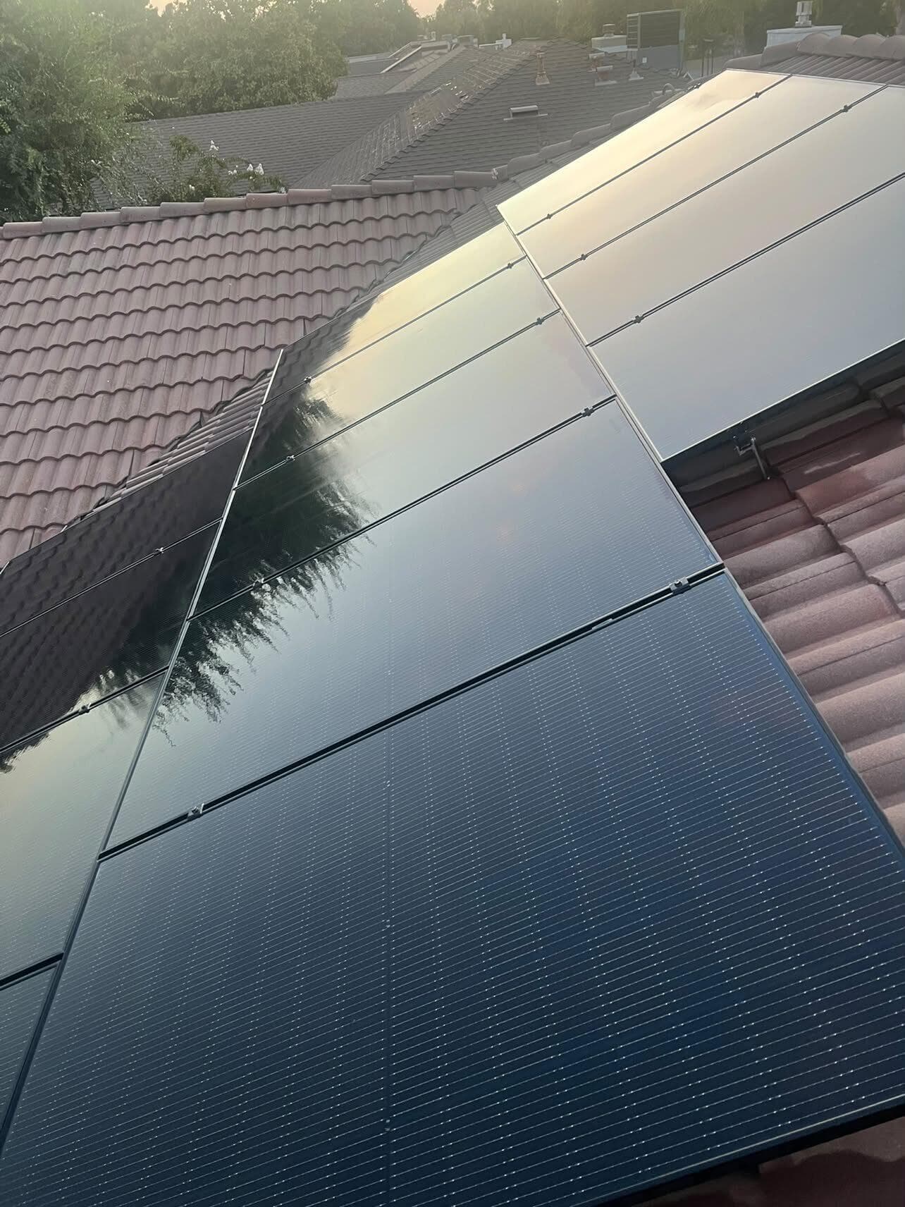 The same tile-roof array freshly cleaned — glossy panels catching the sunset
