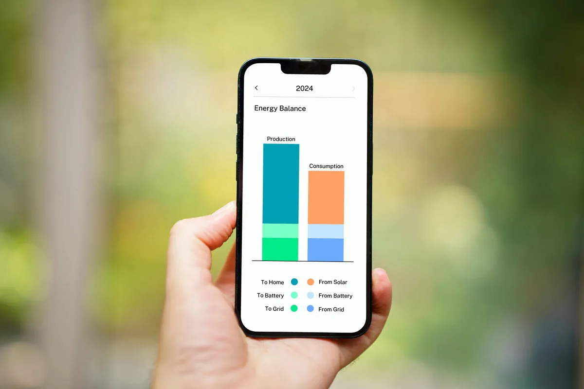 Checking a solar monitoring app on a phone showing production and consumption